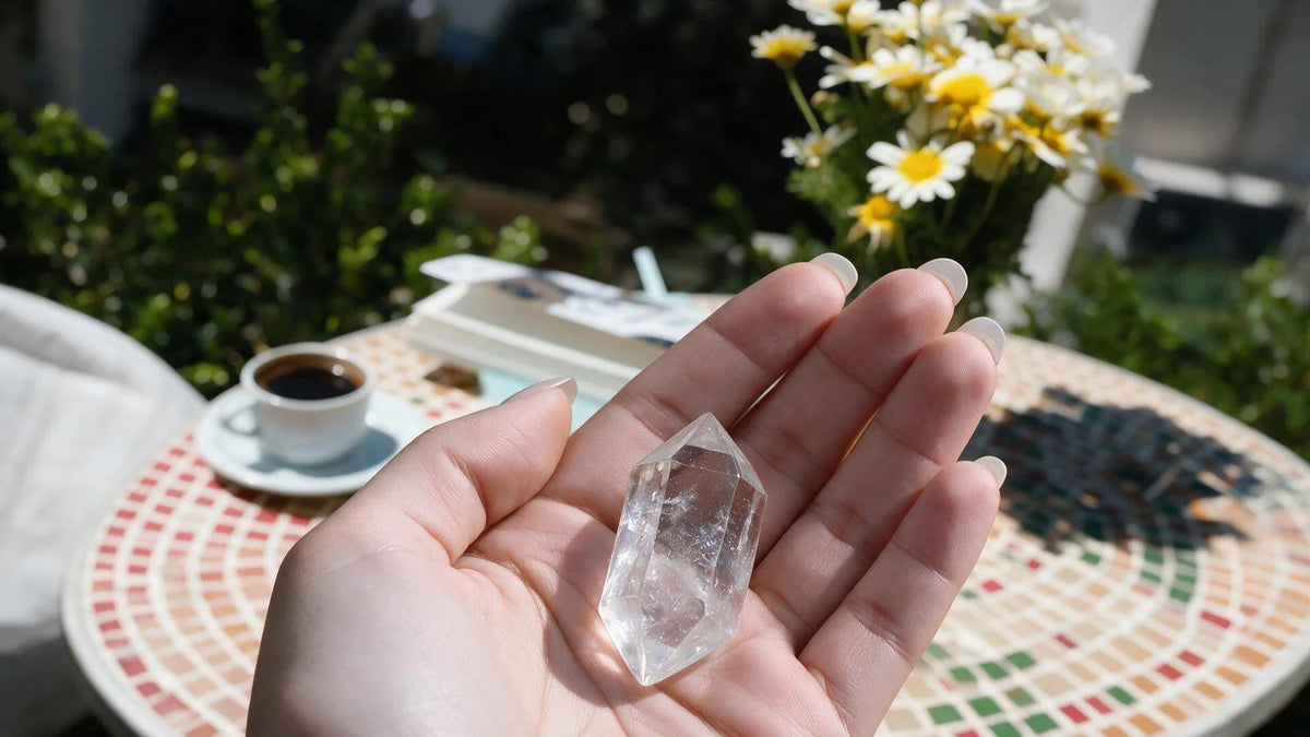 Natural double-terminated quartz floater crystal resting in open palm under natural sunlight.