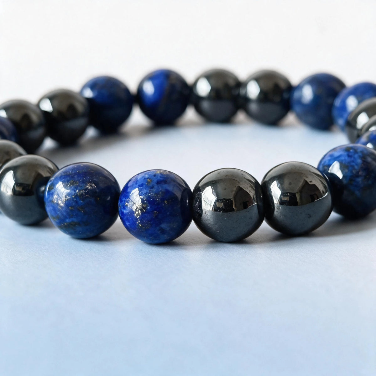 Close-up of natural royal blue lapis lazuli and mirrored hematite weighted bracelet — True North by Ember Quiet.