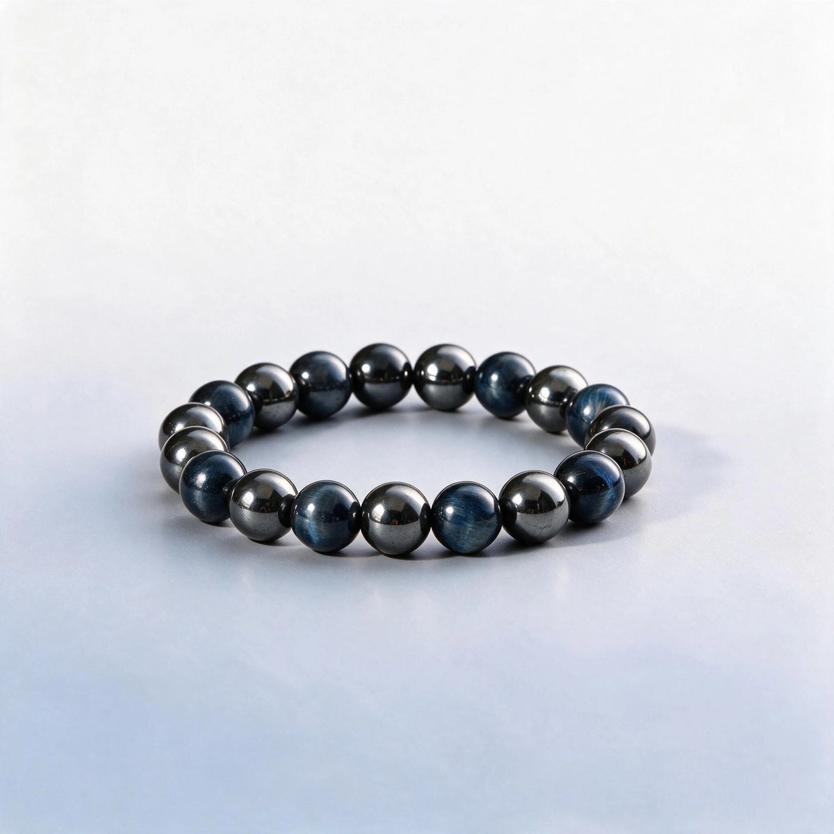 Handcrafted Third Eye & Root Chakra bracelet featuring blue hawk's eye and metallic hematite by Ember Quiet.