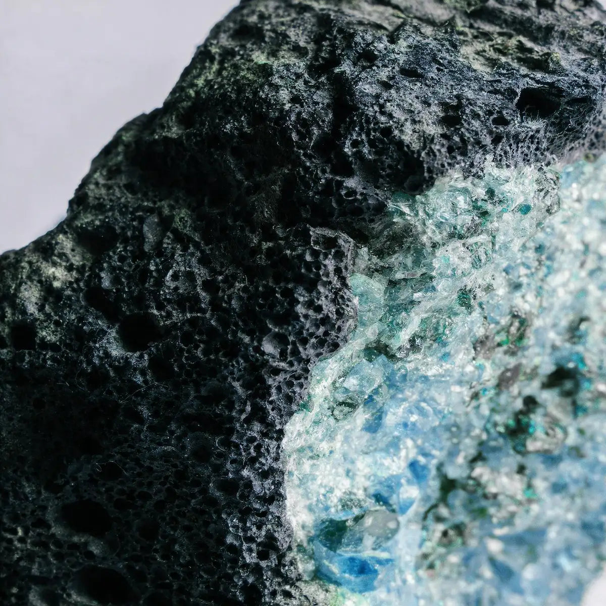 Raw volcanic rock encasing luminous blue crystal minerals, nature's ancient living embers by Ember Quiet.