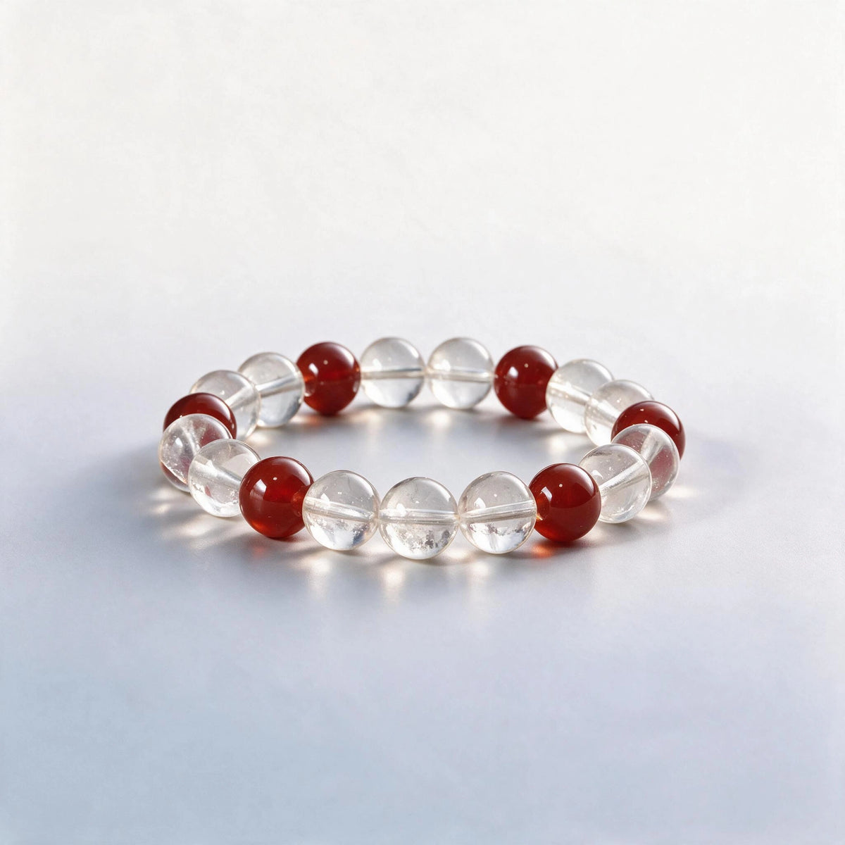 Handcrafted Crown & Root Chakra bracelet featuring natural clear quartz and red agate beads by Ember Quiet.
