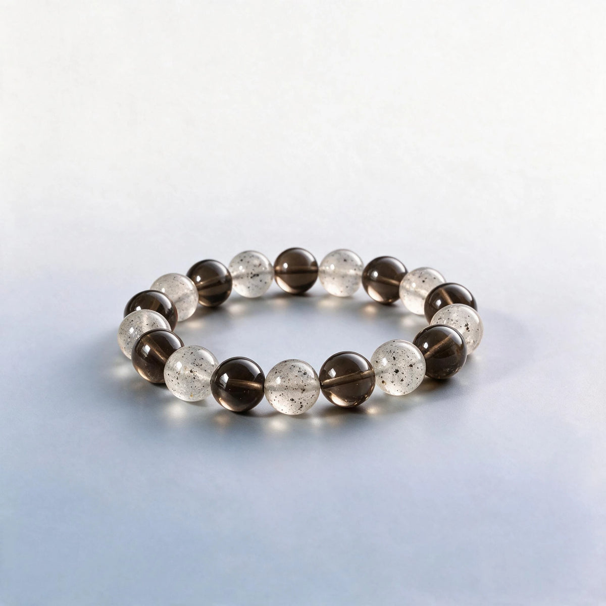 Handcrafted Root Chakra bracelet featuring natural smoky quartz and black strawberry quartz beads by Ember Quiet.
