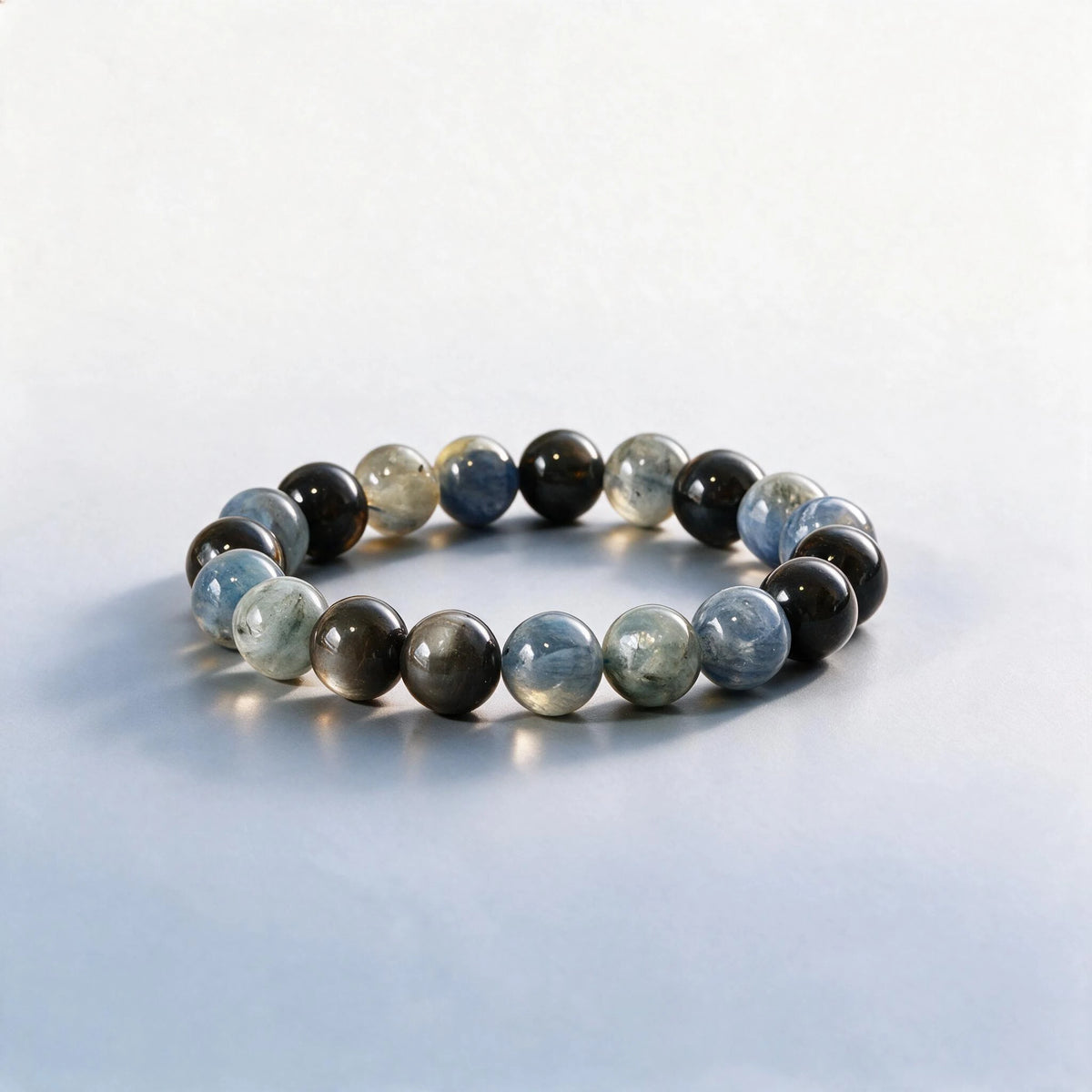 Handcrafted Throat & Third Eye Chakra bracelet featuring blue kyanite and silver sheen obsidian by Ember Quiet.