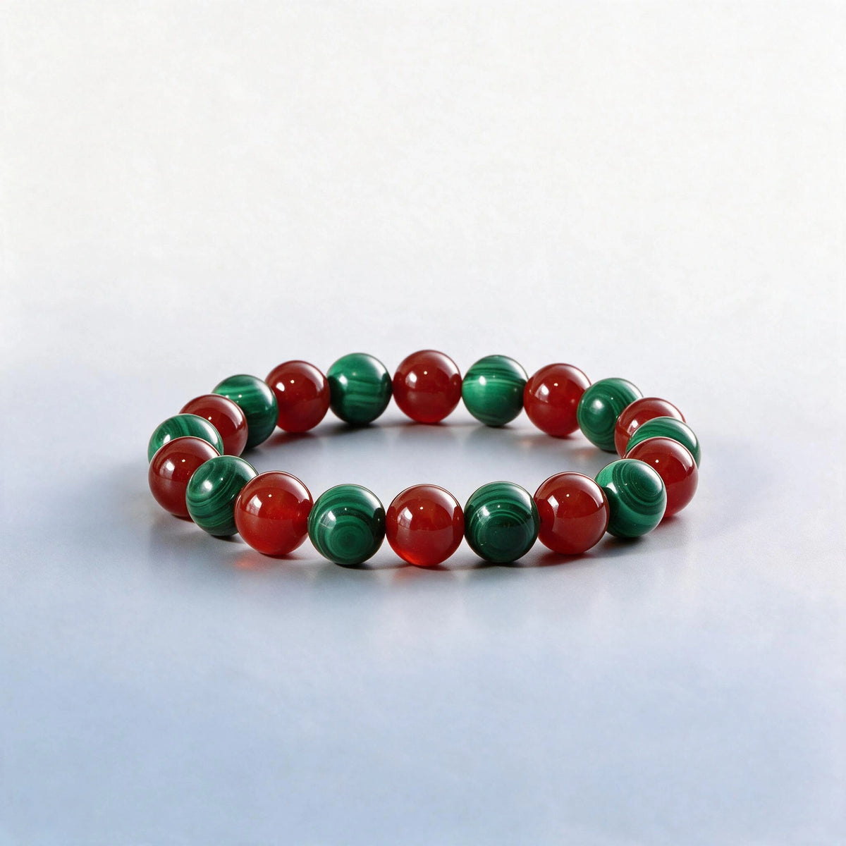 Handcrafted Heart and Root Chakra bracelet featuring natural banded green malachite and red agate beads.